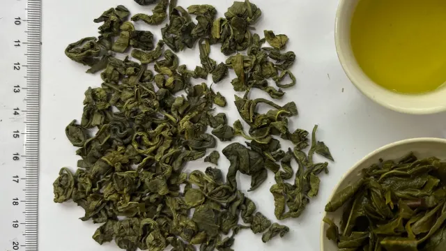 BOM green tea sample from Goo Farm: rolled dry leaf beside a ruler, bright yellow-green liquor and infused leaf